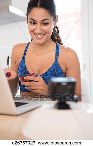 Woman making video call while having fruits View Large Photo Image Stock Photo - Woman making video call while having fruits. Fotosearch