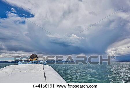 Stock Image - Woman on boat, looking at view, rear view, Huarina, La Paz, Bolivia, South America. Fotosearch