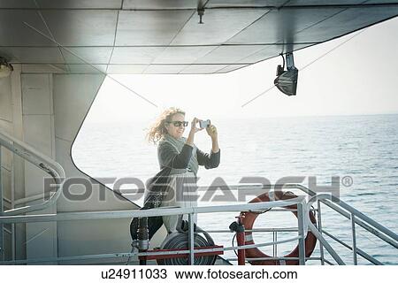 Stock Image - Woman on ferry taking photograph. Fotosearch