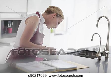 Stock Photo - Woman preparing meal in kitchen. Fotosearch