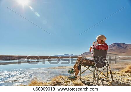 Stock Photo - Woman sitting in camping chair, looking at view, Salar de Chalviri, Chalviri, Oruro, Bolivia, South America. Fotosearch