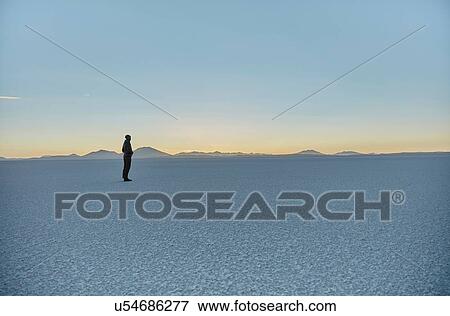 Stock Photo - Woman standing on salt flats, looking at view, Salar de Uyuni, Uyuni, Oruro, Bolivia, South America. Fotosearch