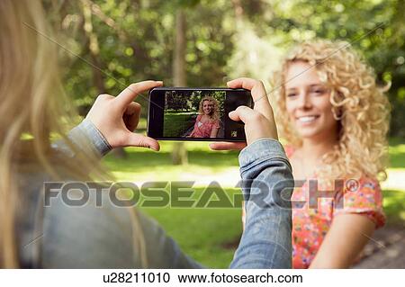 Woman taking photograph of friend using smartphone View Large Photo Image Stock Image - Woman taking photograph of friend using smartphone. Fotosearch