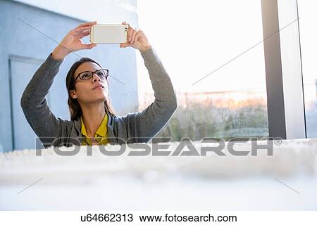 Stock Image - Woman taking photograph of town model. Fotosearch