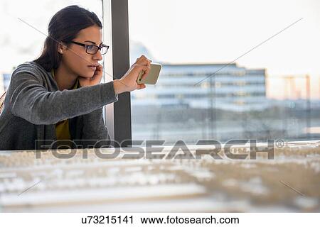 Stock Image - Woman taking photograph of town model. Fotosearch