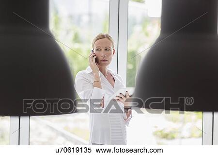 Woman talking on phone and using digital tablet View Large Photo Image Stock Photography - Woman talking on phone and using digital tablet. Fotosearch