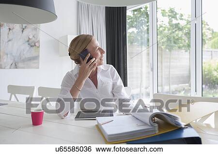 Woman talking on phone in dining room View Large Photo Image Stock Photograph - Woman talking on phone in dining room. Fotosearch