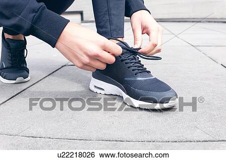 Stock Photograph - Woman tying trainers.. Fotosearch