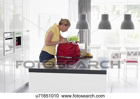 Woman unpacking groceries from shopping bag View Large Photo Image Stock Image - Woman unpacking groceries from shopping bag. Fotosearch