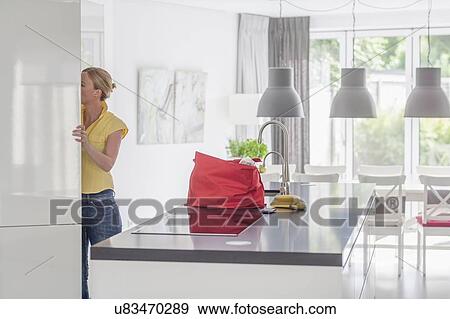 Stock Photo - Woman unpacking groceries from shopping bag. Fotosearch