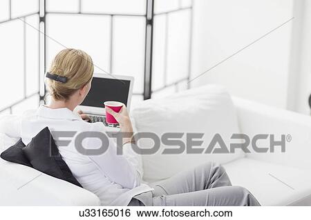 Stock Photograph - Woman using laptop in living room. Fotosearch