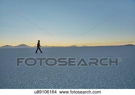Picture - Woman walking across salt flats, Salar de Uyuni, Uyuni, Oruro, Bolivia, South America. Fotosearch