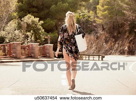 Picture - Woman walking along road, rear view, Sitges, Catalonia, Spain. Fotosearch