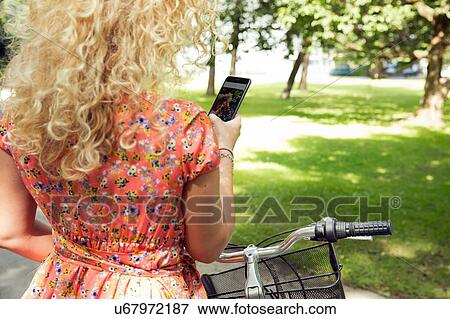 Woman with bicycle using smartphone View Large Photo Image Stock Photo - Woman with bicycle using smartphone. Fotosearch