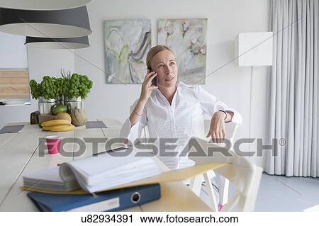 Woman working and talking on phone in dining room View Large Photo Image Stock Image - Woman working and talking on phone in dining room. Fotosearch