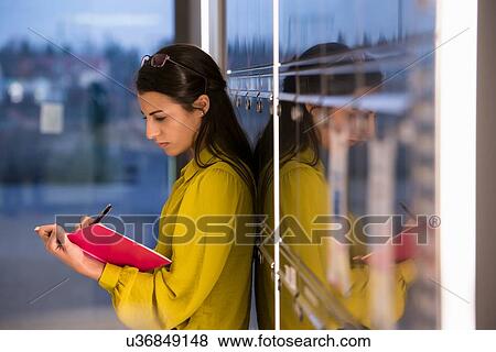 Stock Photo - Woman writing in notepad at office. Fotosearch
