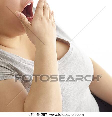 Stock Photo - Woman yawning with hand over mouth.. Fotosearch