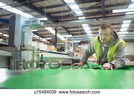 Worker operating vinyl cutting machine in factory View Large Photo Image Stock Photo - Worker operating vinyl cutting machine in factory. Fotosearch