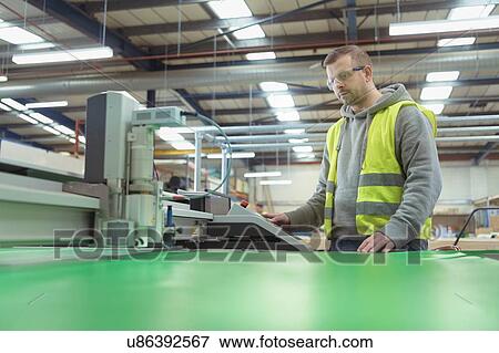 Worker operating vinyl cutting machine in factory View Large Photo Image Stock Photo - Worker operating vinyl cutting machine in factory. Fotosearch