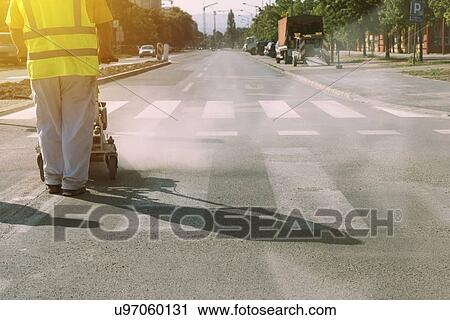 Stock Image - Worker painting pedestrian crossing.. Fotosearch