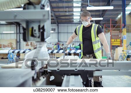 Worker using wood cutting machine in factory View Large Photo Image Stock Photo - Worker using wood cutting machine in factory. Fotosearch