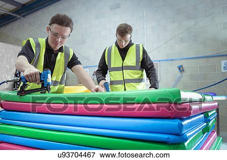 Workers assembling soft coloured mats in factory View Large Photo Image Stock Photo - Workers assembling soft coloured mats in factory. Fotosearch