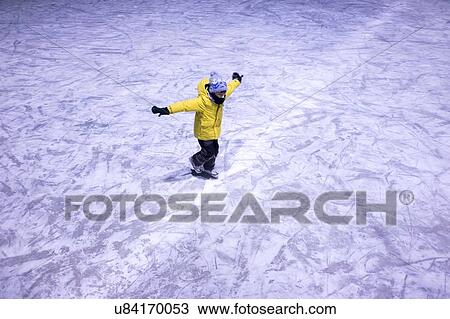 Stock Image - Young boy ice skating, elevated view. Fotosearch
