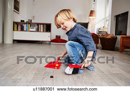 Stock Image - Young boy playing with toy dustpan and brush. Fotosearch