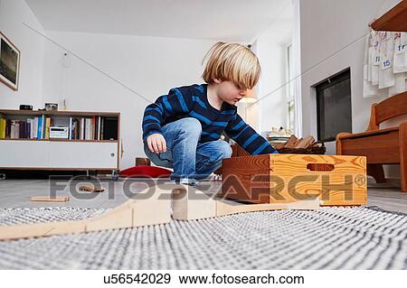 Young boy playing with toys in living room, low angle view View Large Photo Image Stock Photo - Young boy playing with toys in living room, low angle view. Fotosearch