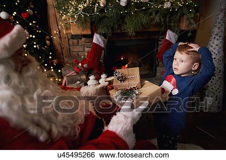 Stock Photograph - Young boy receiving gifts from Santa. Fotosearch