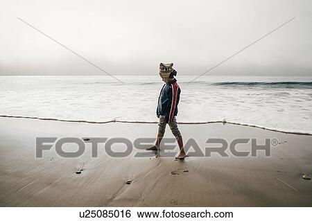 Young boy standing on beach, looking away View Large Photo Image Stock Photograph - Young boy standing on beach, looking away. Fotosearch