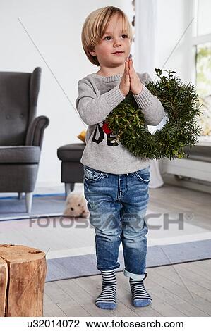 Young boy standing with hands together, holding wreath over arm View Large Photo Image Stock Image - Young boy standing with hands together, holding wreath over arm. Fotosearch