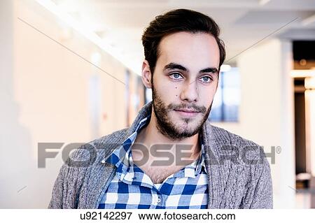 Stock Photo - Young businessman contemplating in office corridor. Fotosearch