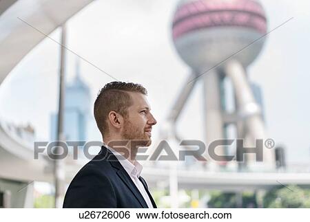 Stock Photograph - Young businessman gazing out at Shanghai financial centre, Shanghai, China. Fotosearch