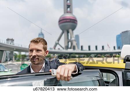 Young businessman getting out of yellow cab at Shanghai financial centre, Shanghai, China View Large Photo Image Stock Image - Young businessman getting out of yellow cab at Shanghai financial centre, Shanghai, China. Fotosearch