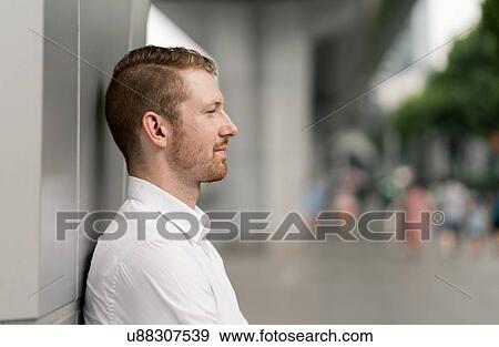 Young businessman leaning against wall in city, Shanghai, China View Large Photo Image Stock Photo - Young businessman leaning against wall in city, Shanghai, China. Fotosearch