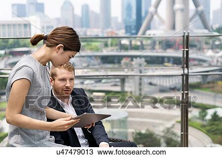 Young businesswoman and man looking at digital tablet at sidewalk cafe in Shanghai financial centre, Shanghai, China View Large Photo Image Stock Image - Young businesswoman and man looking at digital tablet at sidewalk cafe in Shanghai financial centre, Shanghai, China. Fotosearch