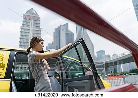 Young businesswoman getting out of yellow cab at Shanghai financial centre, Shanghai, China View Large Photo Image Stock Image - Young businesswoman getting out of yellow cab at Shanghai financial centre, Shanghai, China. Fotosearch