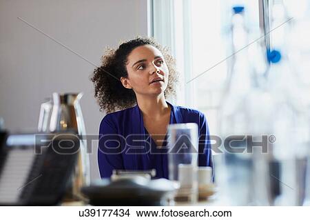 Picture - Young businesswoman listening at boardroom table. Fotosearch
