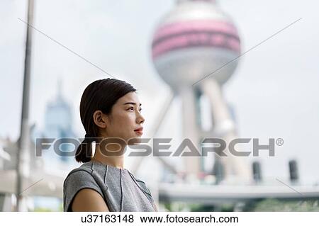 Stock Photo - Young businesswoman looking out at Shanghai financial centre, Shanghai, China. Fotosearch
