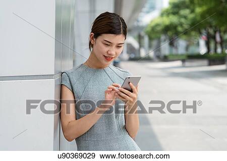 Young businesswoman using smartphone touchscreen in city, Shanghai, China View Large Photo Image Stock Photo - Young businesswoman using smartphone touchscreen in city, Shanghai, China. Fotosearch