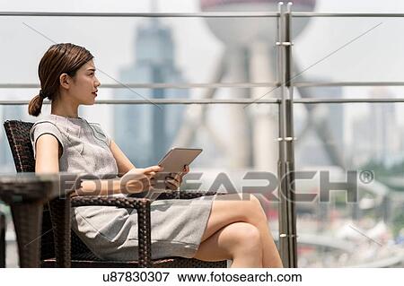 Young businesswoman with digital tablet at sidewalk cafe in Shanghai financial centre, Shanghai, China View Large Photo Image Stock Photo - Young businesswoman with digital tablet at sidewalk cafe in Shanghai financial centre, Shanghai, China. Fotosearch