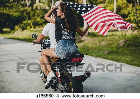 Young couple holding up American flag while riding motorcycle on rural road, Krabi, Thailand, rear view View Large Photo Image Stock Image - Young couple holding up American flag while riding motorcycle on rural road, Krabi, Thailand, rear view. Fotosearch