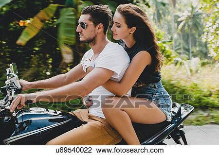 Stock Image - Young couple riding on motorcycle on rural road, Krabi, Thailand. Fotosearch