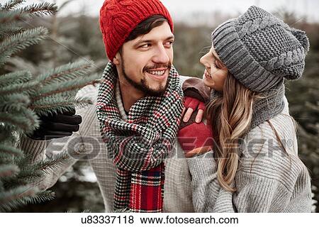 Stock Photo - Young couple selecting christmas tree from forest. Fotosearch