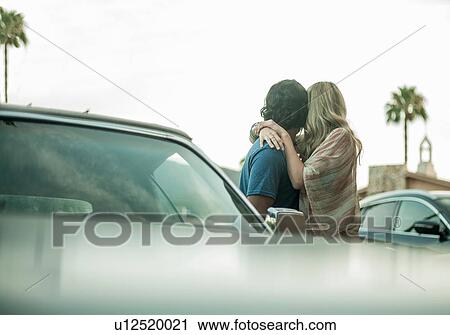 Young couple, standing beside car, hugging, looking away View Large Photo Image Stock Image - Young couple, standing beside car, hugging, looking away. Fotosearch