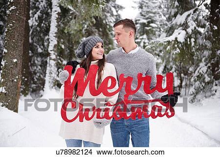 Picture - Young couple with Merry Christmas words in snow. Fotosearch