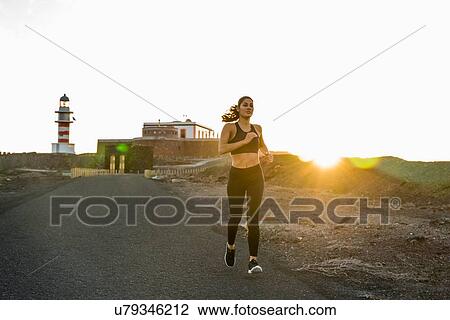 Young female runner running down rural road at sunset, Las Palmas, Canary Islands, Spain View Large Photo Image Stock Image - Young female runner running down rural road at sunset, Las Palmas, Canary Islands, Spain. Fotosearch