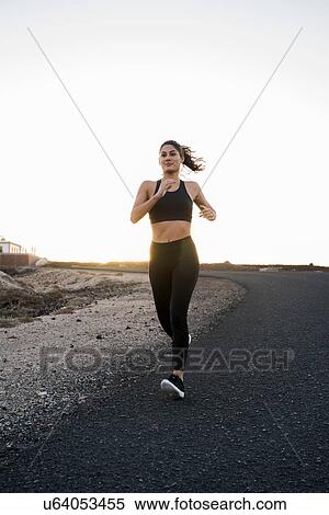 Young female runner running down rural road View Large Photo Image Stock Photography - Young female runner running down rural road. Fotosearch