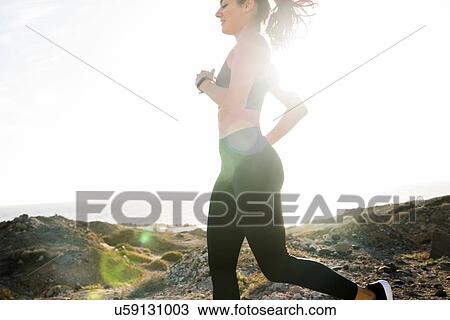 Stock Image - Young female runner running near coast, Las Palmas, Canary Islands, Spain. Fotosearch